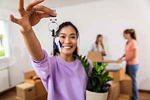 a new homeowner holding her keys after buying homeowners insurance