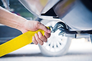 A person hooking up a clamp to a car that needs to be towed