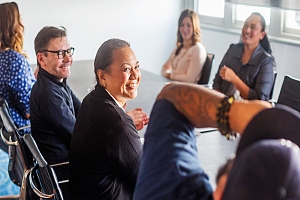 Business employees sitting at a conference table smiling and laughing to each other