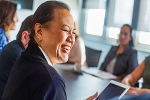 Woman laughing with her coworkers at a conference meeting
