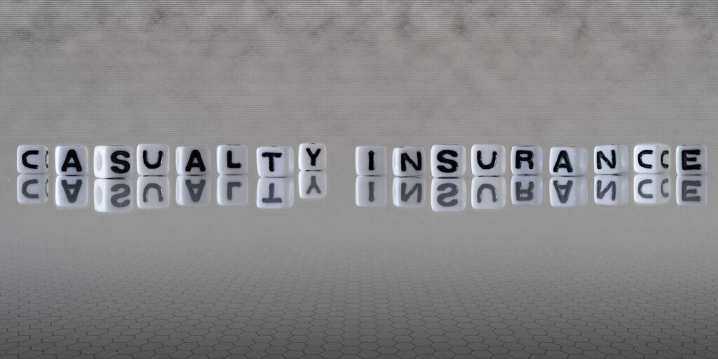 casualty insurance word or concept represented by black and white letter cubes on a grey horizon background stretching to infinity