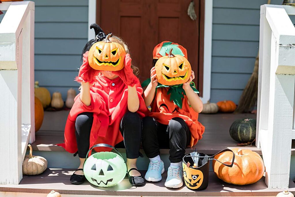 children celebrating halloween in costume and wearing pumpkin heads