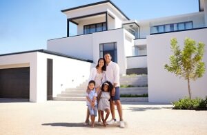 Portrait, real estate and happy family moving into their new luxury home, house or property in summer. Happy parents and children standing with a smile outdoor with building investment or purchase