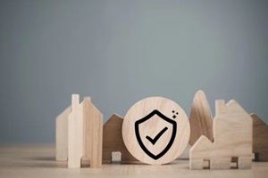 shield icon on a piece of wood and small wooden houses placed around it