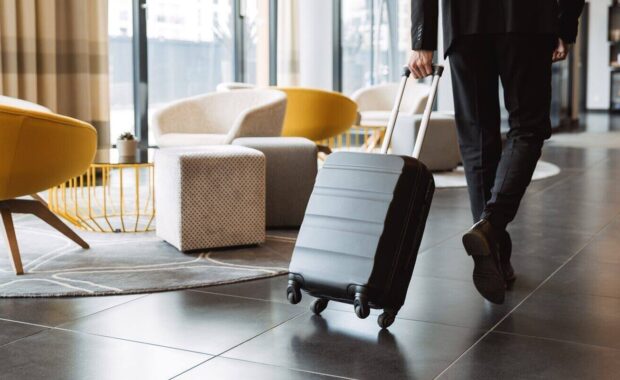 businessman wearing suit walking with suitcase in hotel lobby