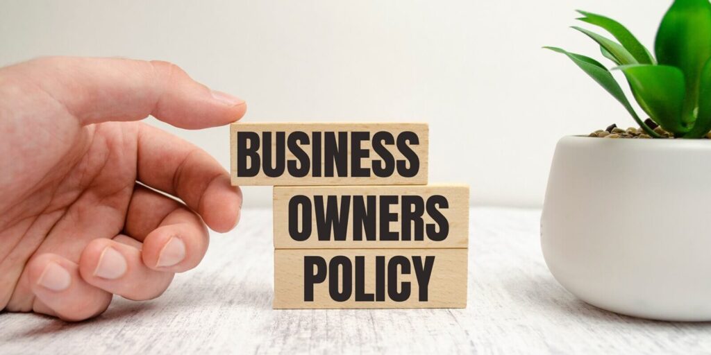 business owners policy words on wooden blocks and plant