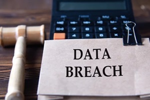 DATA BREACH - words on light brown paper against the background of a calculator and a judge's gavel