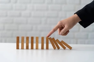 business woman's hands stopping falling wooden dominoes Financial hedging concept