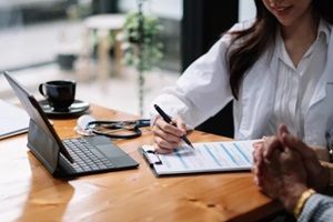 female health insurance broker presenting his insurance benefits to Hawaii businessman fill out insurance policy