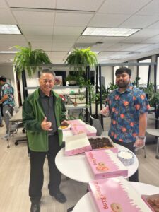 this is a photo of two employees at Atlas Insurance Agency where they are eating and enjoying donuts from Donut King Hawaii