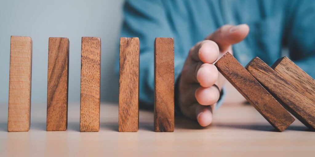 Hawaii businessman hand obstruct rectangle block which falling to stop dominos others rectangle standing for risk assessment and crisis management concept