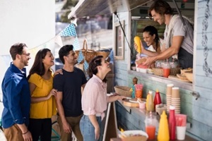 smiling waiter giving order to customers at counter to represent small business insurance