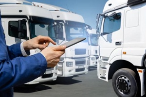 Hawaii fleet manager with digital tablet on a background of commercial trucks