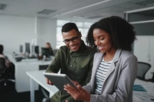 smiling young african american professional businessman and businesswoman together working online with a digital tablet in office