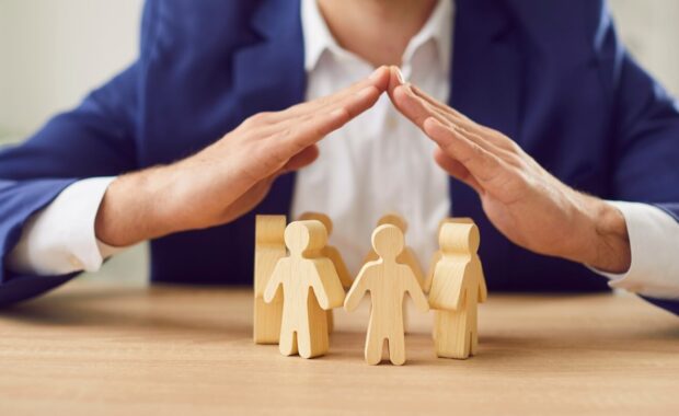 non-profit owner covering wooden figures of people to represent insurance