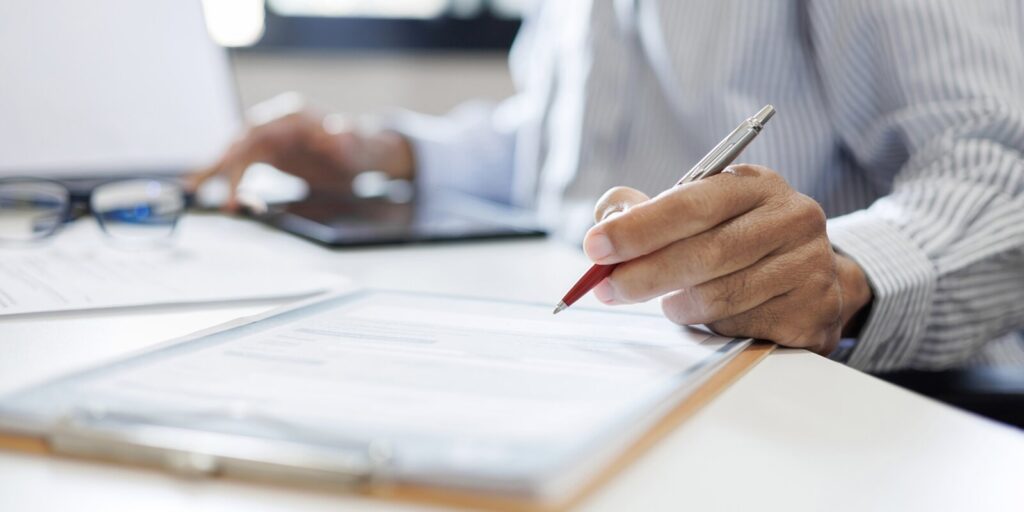 close-up shot, Hawaii businessman reviewing document at office workplace with computer laptop
