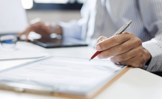 close-up shot, Hawaii businessman reviewing document at office workplace with computer laptop