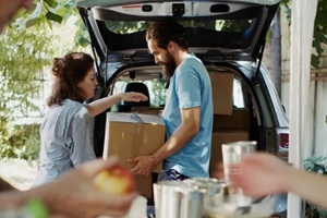 male volunteer gives donation boxes from the car to the needy and less privileged individuals