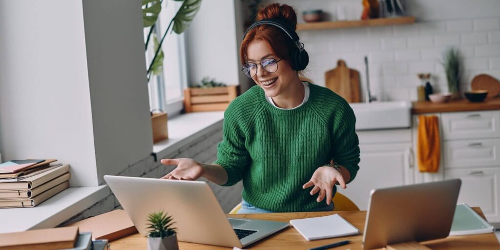 cheerful young woman in headphones having web conference while working from home in Hawaii
