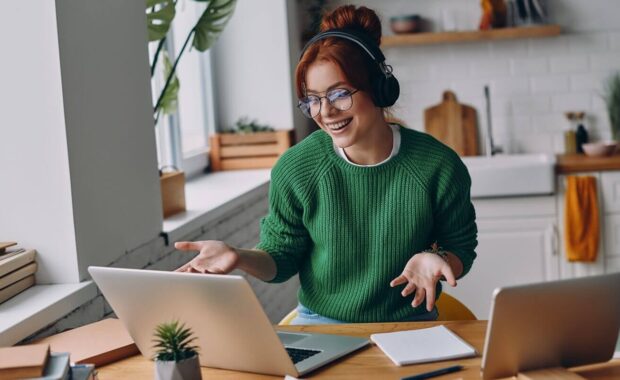 cheerful young woman in headphones having web conference while working from home in Hawaii