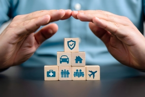 Hands Protect Wooden Blocks with Icons Representing Insurance Types