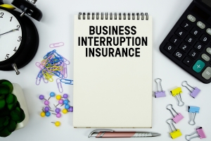 Business Interruption Insurance Text Written on Notepad with Calculator and Alarm Clock