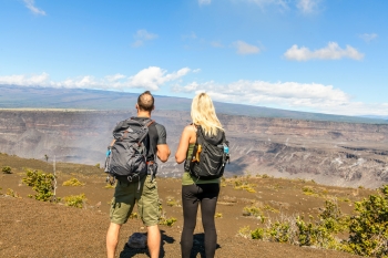 Hiking couple seeing volcano national park from crater on the caldera Halemaumau around Hawaii volcanoes national park