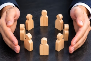 Business Leader Hands Protecting Wooden Employee Figures Representing Employee Group Health Inusrance Concept