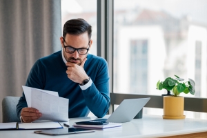 Serious Young Business Executive Reading Insurance Premium Documents