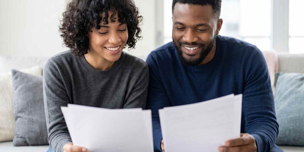 Smiling Couple Comparing Homeowners Insurance Documents in Honolulu