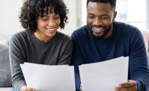 Smiling Couple Comparing Homeowners Insurance Documents in Honolulu
